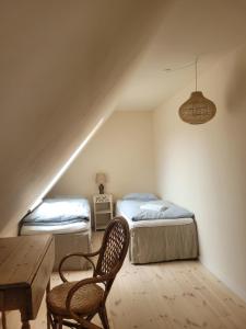 2 camas en una habitación con mesa y silla en Atma Guesthouse - cozy and simple bed & breakfast in the countryside, en Marstal