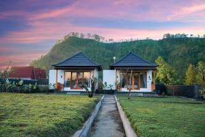a house in a field with a mountain in the background at Hillside bali in Kubupenlokan