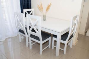 a white dining room table and four white chairs at Staycation with les in Eldoret