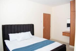 uma cama com uma cabeceira preta num quarto em Staycation with les em Eldoret