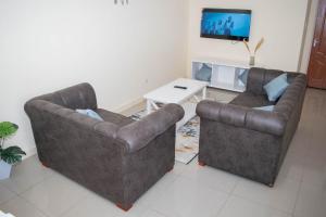 een woonkamer met 2 banken en een tv bij Staycation with les in Eldoret