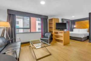 a hotel room with a bed and a couch and a tv at Roomzzz Leeds City West in Leeds