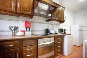 uma cozinha com armários de madeira e um frigorífico branco em Akademia House - Cantinho da Nazaré na Nazaré