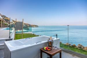 uma banheira numa varanda com vista para o oceano em Rocca al Mare Seaside Villas em Palaiokastro