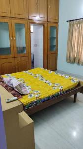 a bed with a yellow blanket on top of it at Ohm Shanthi Homestay in Pondicherry