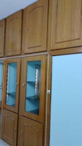 a wooden cabinet with glass doors in a room at Ohm Shanthi Homestay in Puducherry