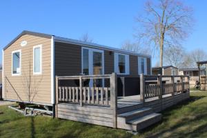 a tiny house with a porch and a deck at Siblu camping in de Bongerd in Oostkapelle