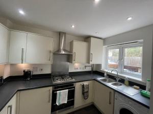 a kitchen with a stove and a sink and a window at Addlestone and Chertsey Stylish and Modern 4 bedroom 4 bathroom Townhouse in Addlestone