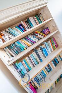 a wooden shelf filled with lots of books at The Waves - Camber Sands - East Sussex in Camber