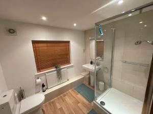 y baño con ducha, aseo y lavamanos. en Beautiful and spacious 4 Bedroom 3 Bathroom property in Central Chertsey, en Chertsey