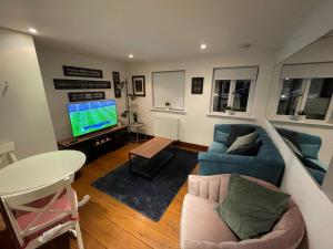 a living room with a blue couch and a tv at Beautiful and spacious 4 Bedroom 3 Bathroom property in Central Chertsey in Chertsey