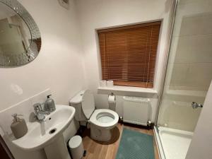y baño con aseo, lavabo y espejo. en Beautiful and spacious 4 Bedroom 3 Bathroom property in Central Chertsey, en Chertsey