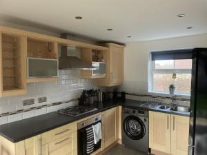 a kitchen with wooden cabinets and a black counter top at Gorgeous 3 Bedroom 2 Bathroom Family Home in Bracknell