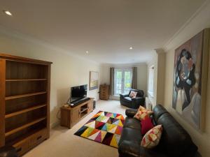 a living room with a leather couch and a television at Henley - Luxurious Spacious Four Bedroom Two Bath in Henley on Thames