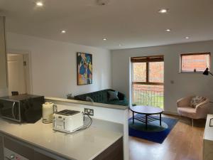 a kitchen with a microwave and a living room at MAIDENHEAD Stylish and modern 2 bedroom apartment in Maidenhead