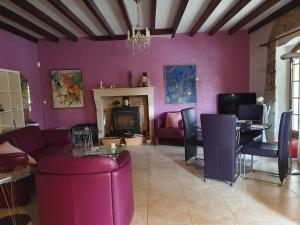 a living room with purple walls and a fireplace at Le Presbytère in Saint-Romain