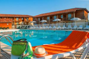 a hotel swimming pool with a hat and a chair at Les Maisons du Golf d'Armagnac in Eauze