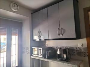 a kitchen with white cabinets and a microwave at LA POSAINA in Serradilla +5 photos
