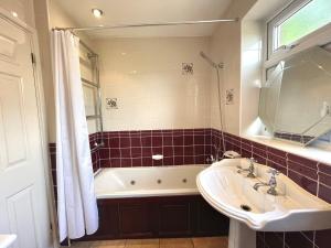 a bathroom with a sink and a tub and a mirror at Chertsey Luxurious Three Bedroom Two Bath Home 3 in Chertsey