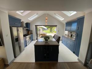 a kitchen with blue cabinets and a island in it at Ascot stunning and modern 4 bedroom town house with 156 sq ft garden office 28 in Ascot