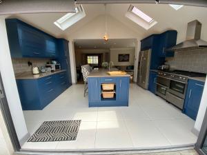 a kitchen with blue cabinets and a white tile floor at Ascot stunning and modern 4 bedroom town house with 156 sq ft garden office 28 in Ascot