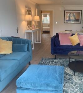 Flat 60, Longborn في ويندسور: غرفة معيشة مع كنبتين زرقاوين وطاولة