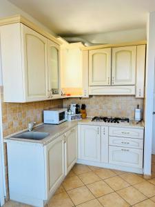 eine Küche mit weißen Schränken und einer weißen Mikrowelle in der Unterkunft Casa Anselmo in Loano