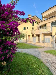 einen Gehweg vor einem Gebäude mit lila Blumen in der Unterkunft Casa Anselmo in Loano