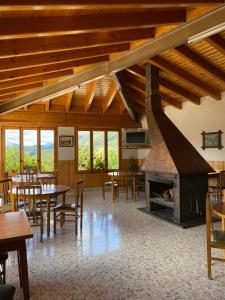 Habitación grande con mesas, sillas y chimenea. en Hostal Alt Llobregat, en Castellar de NʼHug