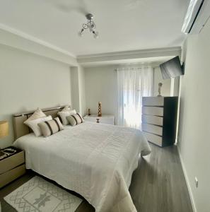 ein weißes Schlafzimmer mit einem großen Bett und einem Fenster in der Unterkunft casa hilario in Nazaré