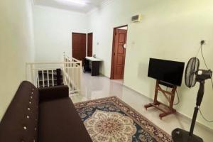 - un salon avec un canapé et une télévision dans l'établissement Kayak D'bali Homestay, à Pasir Puteh