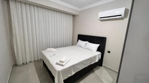Dormitorio pequeño con cama con sábanas y almohadas blancas en Selinti City Tatil Evleri1&1, en Gazipasa