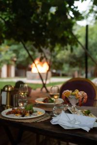 una mesa de madera con platos de comida y copas de vino en ALANYA BUNGALOW EVLERİ / RESTAURANT en Asmaca