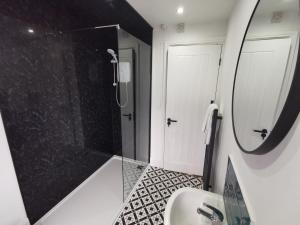 a bathroom with a shower and a sink and a mirror at Large 5 Bed House, 9 Beds + Parking + 3 bathrooms in Wirral