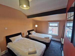 a hotel room with two beds and a window at Large 5 Bed House, 9 Beds + Parking + 3 bathrooms in Wirral