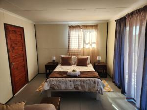um quarto com uma cama grande e uma janela em Cozy Cabin Country Cottage em Skeerpoort