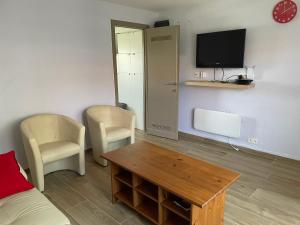 a living room with a couch and a table and a tv at Chouette appartement 5 personnes in De Haan