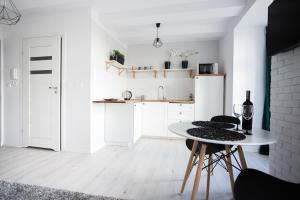 トルンにあるPrzytulny Apartament przy Starym Mieścieの白いキッチン(テーブル、椅子付)