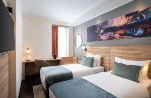 a hotel room with two beds and a tv at Leonardo Boutique Hotel Linz City Center in Linz