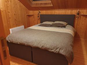 ein Schlafzimmer mit einem Bett in einem Holzzimmer in der Unterkunft Chalet Bonne Humeur in Houffalize