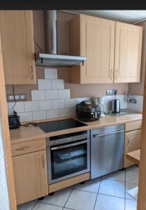 eine Küche mit Holzschränken und Edelstahlgeräten in der Unterkunft Schöne Gartenwohnung Düsseldorf in Düsseldorf