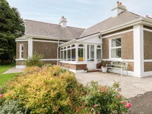 uma casa com um alpendre com um banco em Churchfield House em Ballina