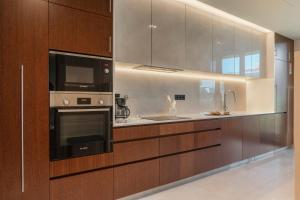 a kitchen with wooden cabinets and a microwave and a sink at Savoy Residence Casa Branca II by An Island Apart in Funchal
