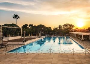 a large swimming pool with a sunset in the background at ROBINSON APULIA - All Inclusive in Ugento