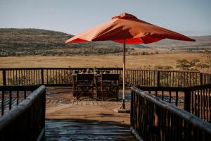 uma mesa com um guarda-chuva num deque de madeira em Matingwe Lodge em Vaalwater