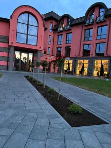 ein rosafarbenes Gebäude mit einem Baum davor in der Unterkunft Hotel Zefir in Drohobytsch