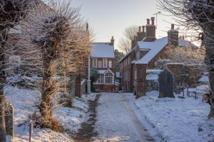 a snow covered street in a town with houses at Sage Cottage in Ditchling