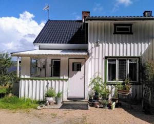 a white house with potted plants in front of it at Lägenhet naturnära i Henån in Henån