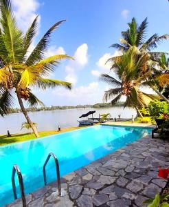 - une piscine avec vue sur l'eau et les palmiers dans l'établissement Chaleni Villa, à Bentota