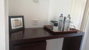 a table with a tray of water bottles and a picture at Chaleni Villa in Bentota